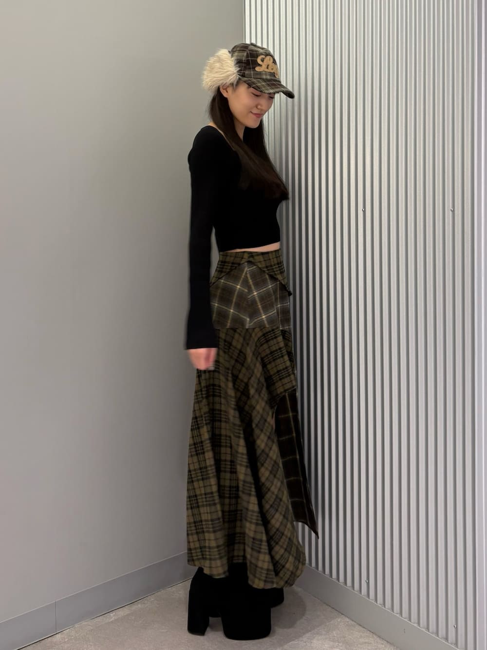 グリーン系のスカート、ブラック系のニット/セーター、ブラック系のブーツを着用したレディースの秋コーディネートの2枚目の写真