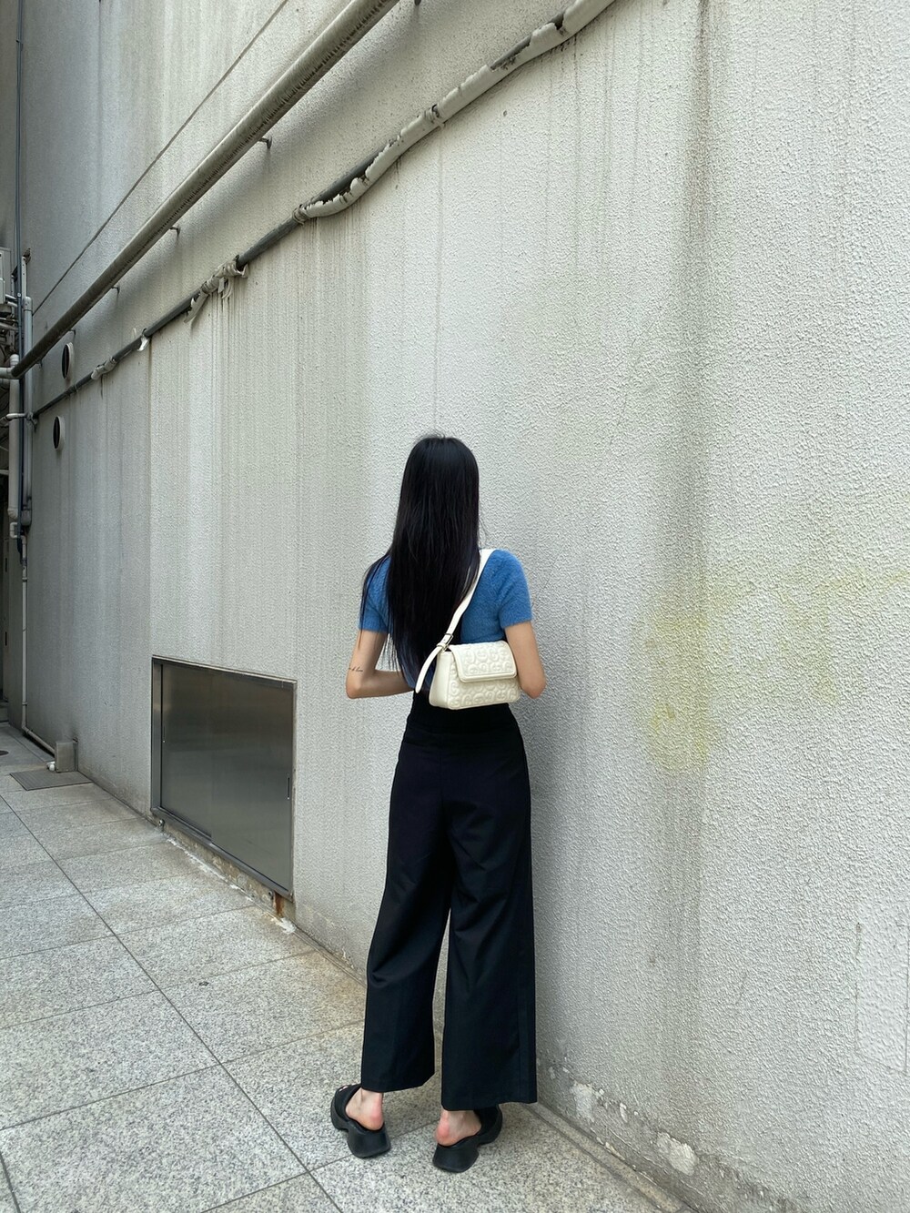 ブラック系のその他パンツ、ホワイト系のハンドバッグ、ブルー系のニット/セーターを着用したレディースの夏コーディネートの5枚目の写真