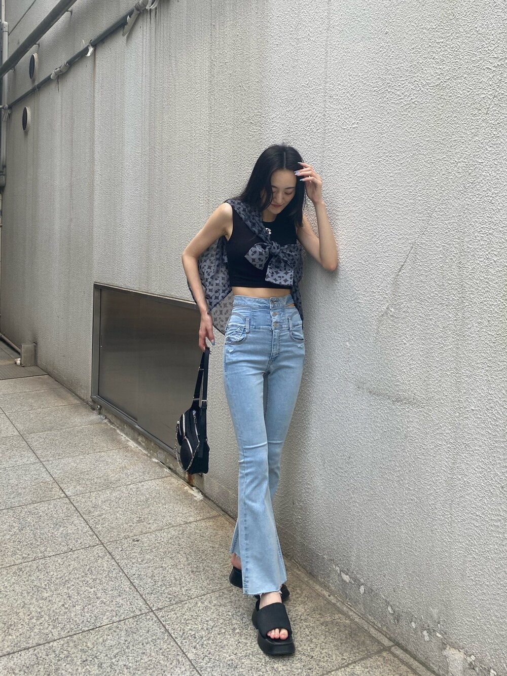 ブルー系のデニムパンツ、ブラック系のハンドバッグ、ブラック系のサンダルを着用したレディースの夏コーディネートの3枚目の写真