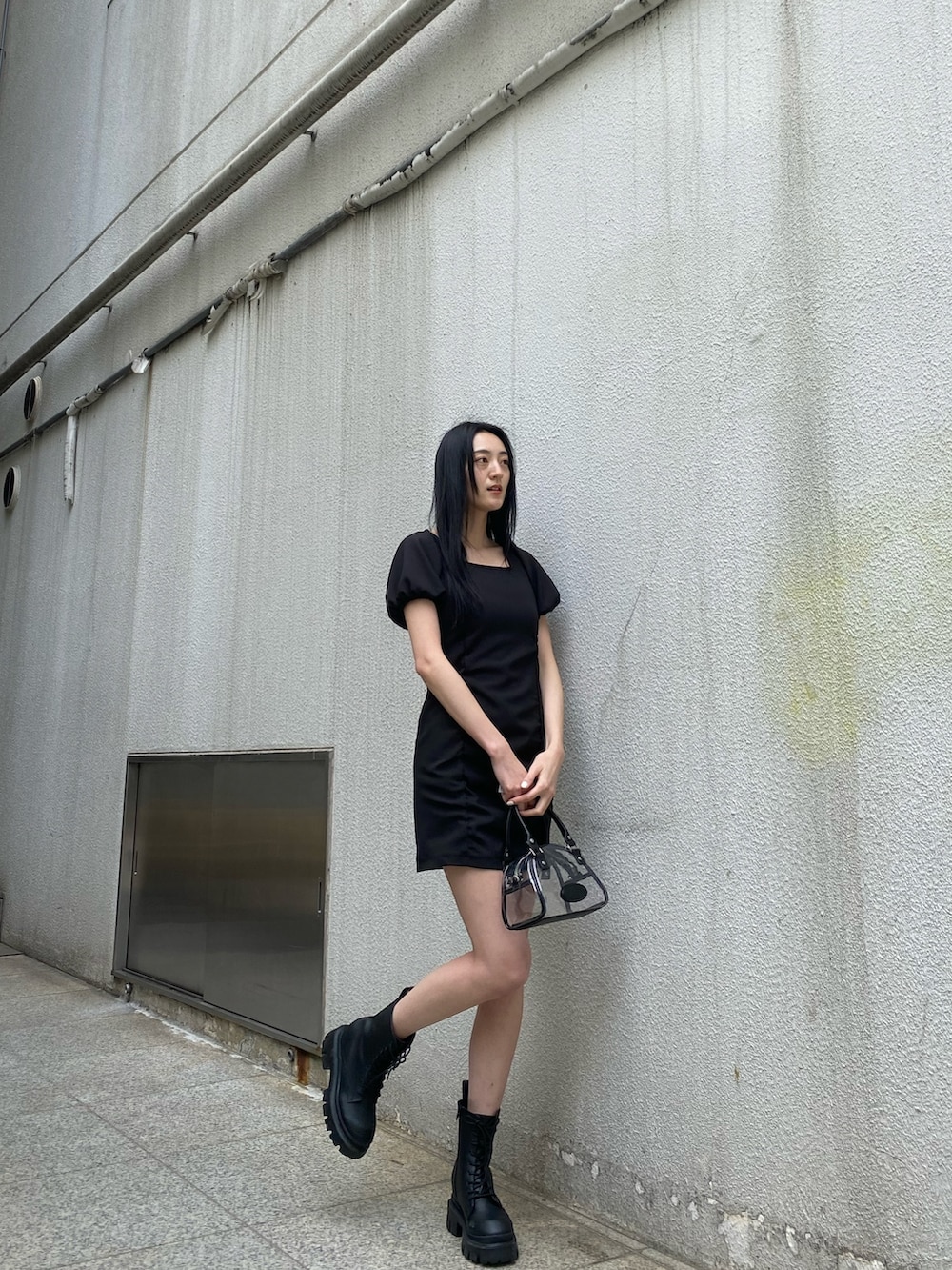 ブラック系のワンピース、ブラック系のブーツ、その他のハンドバッグを着用したレディースの春コーディネートの4枚目の写真