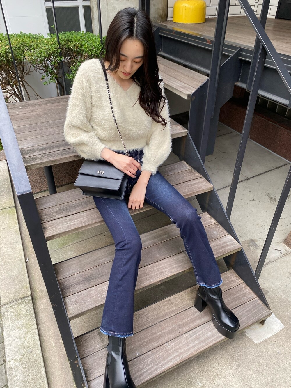 ブラック系のハンドバッグ、ブルー系のデニムパンツ、ホワイト系のニット/セーターを着用したレディースの冬コーディネートの3枚目の写真