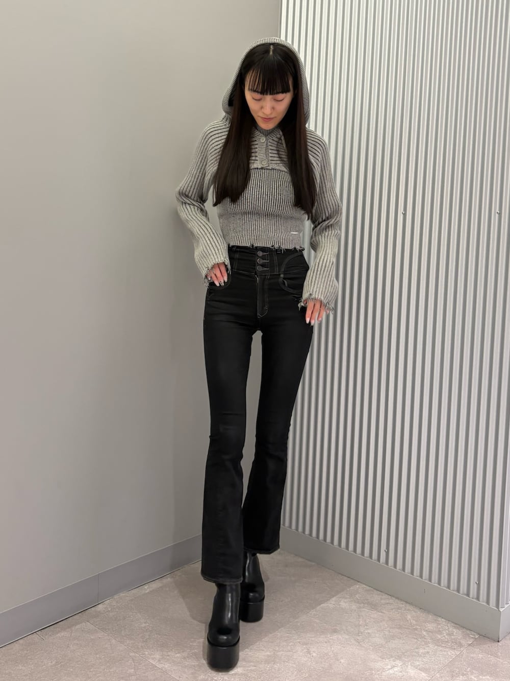 ブラック系のデニムパンツ、ブラック系のブーツ、グレー系のニット/セーターを着用したレディースの秋コーディネートの2枚目の写真