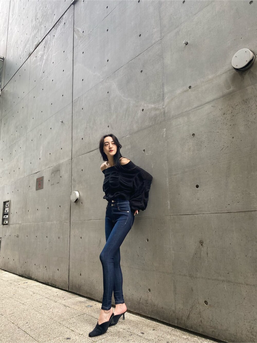 ブラック系のパンプス、ブルー系のデニムパンツ、ブラック系のニット/セーターを着用したレディースの秋コーディネートの2枚目の写真