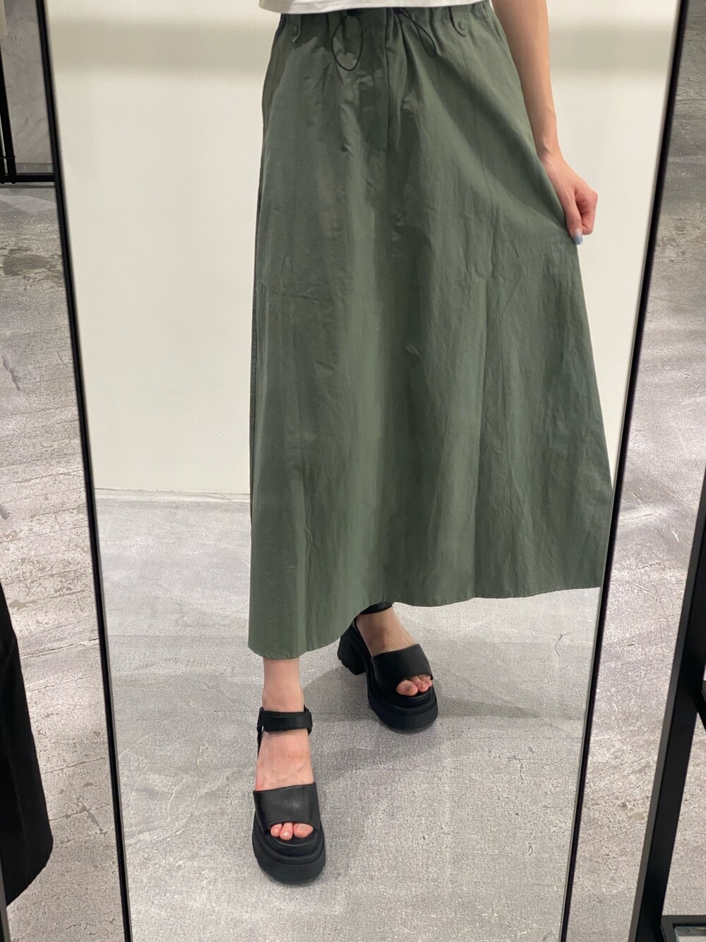 グリーン系のスカート、ブラック系のTシャツ/カットソー、ブラック系のサンダルを着用したレディースの夏コーディネートの4枚目の写真