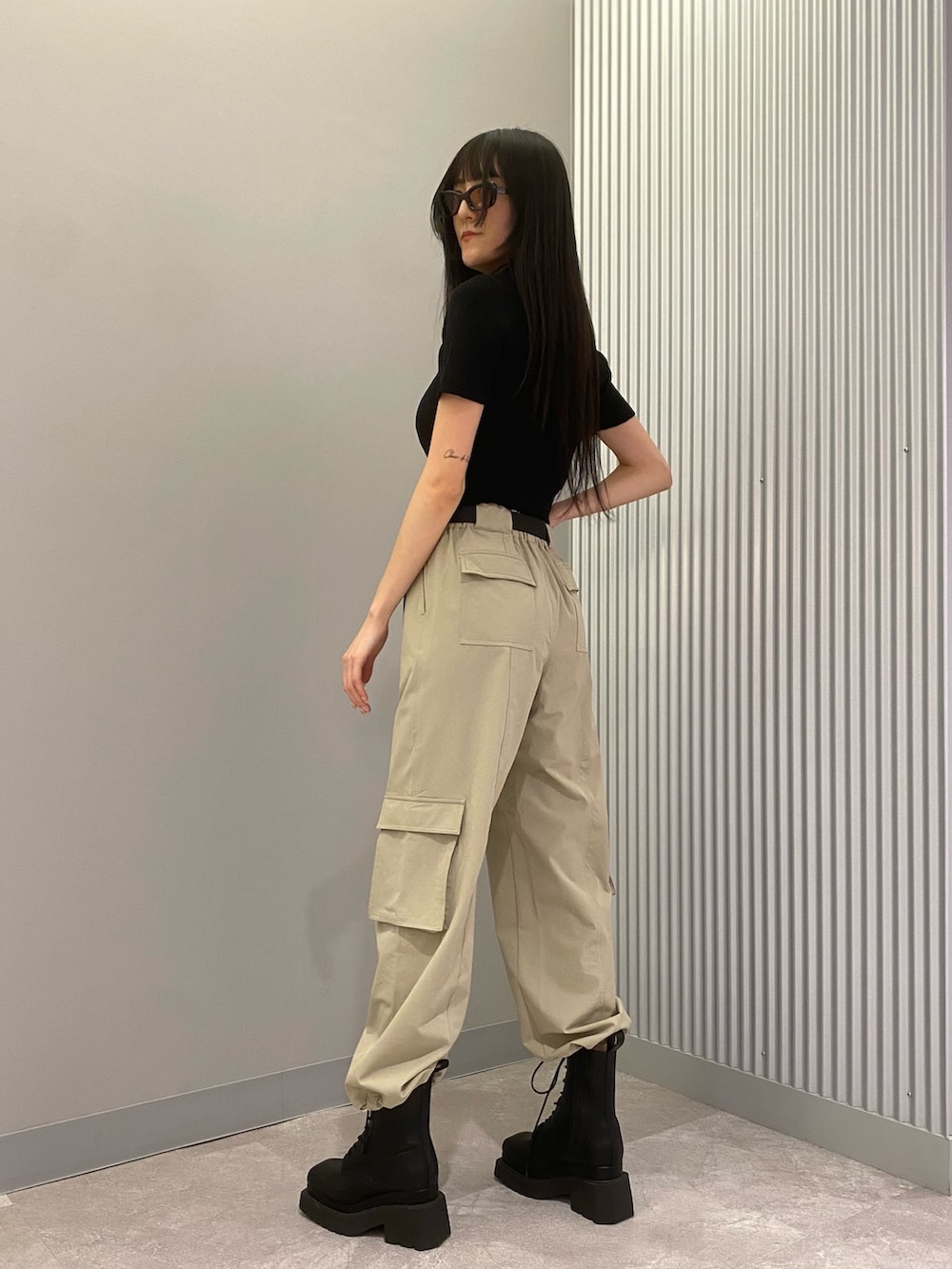 ベージュ系のカーゴパンツ、ブラック系のニット/セーター、ブラック系のブーツを着用したレディースの春コーディネートの2枚目の写真