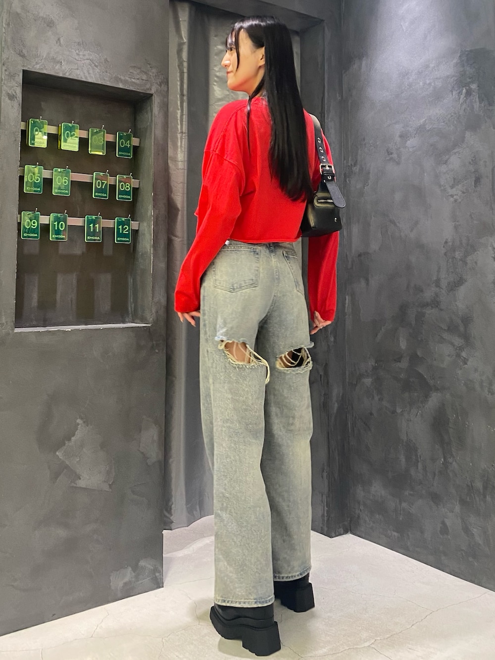 ブルー系のデニムパンツ、ブラック系のハンドバッグ、レッド系のTシャツ/カットソーを着用したレディースの秋コーディネートの3枚目の写真