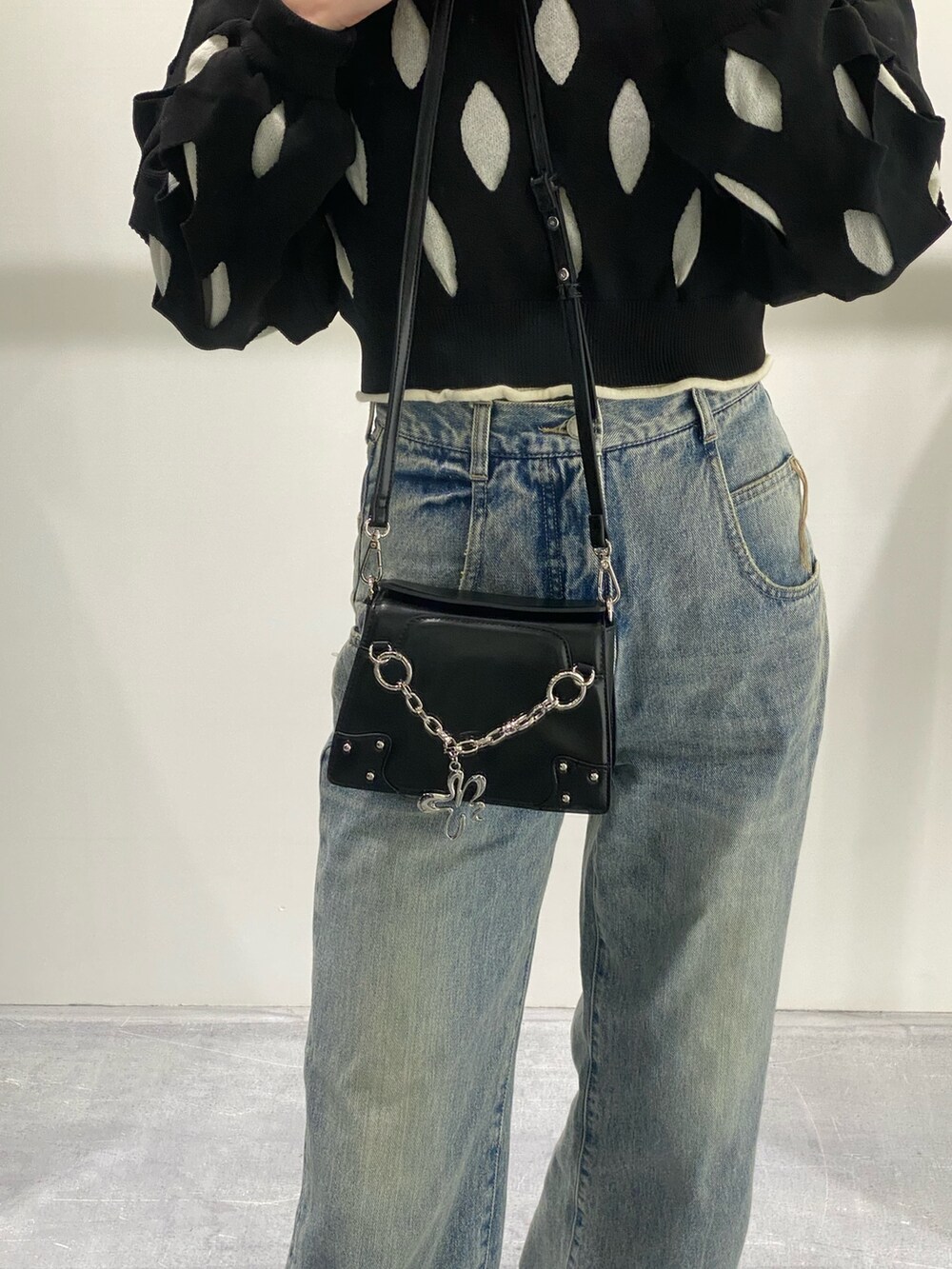 ブルー系のデニムパンツ、ブラック系のニット/セーター、ブラック系のショルダーバッグを着用したレディースの冬コーディネートの7枚目の写真