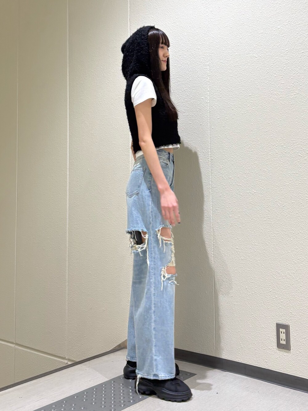 ホワイト系のTシャツ/カットソー、ブラック系のニット/セーター、ブルー系のデニムパンツを着用したレディースの春コーディネートの4枚目の写真