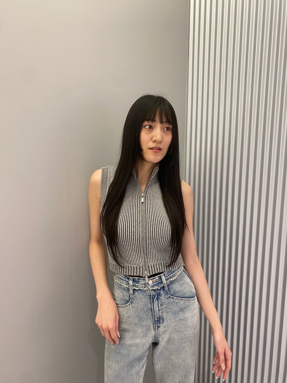 ブルー系のデニムパンツ、グレー系のニット/セーター、ブラック系のサンダルを着用したレディースの春コーディネートの5枚目の写真