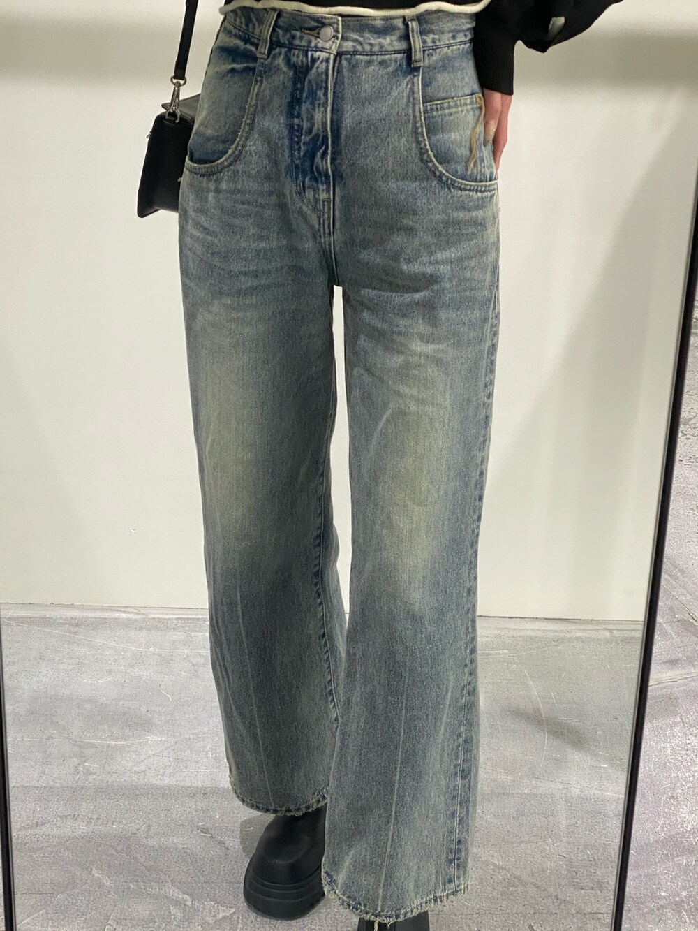 ブルー系のデニムパンツ、ブラック系のニット/セーター、ブラック系のショルダーバッグを着用したレディースの冬コーディネートの4枚目の写真