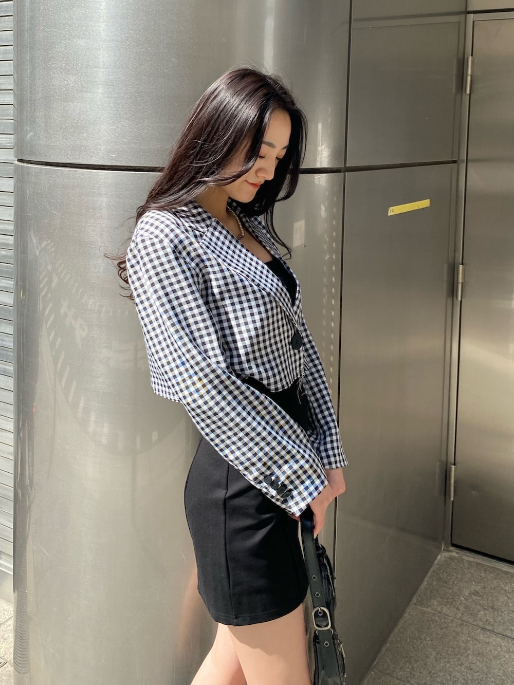 ブラック系のブーツ、ブラック系のスカート、ブラック系のハンドバッグを着用したレディースの春コーディネートの5枚目の写真