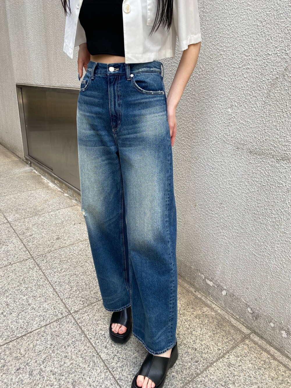 ブルー系のデニムパンツ、ブラック系のニット/セーター、ホワイト系のシャツ/ブラウスを着用したレディースの春コーディネートの7枚目の写真