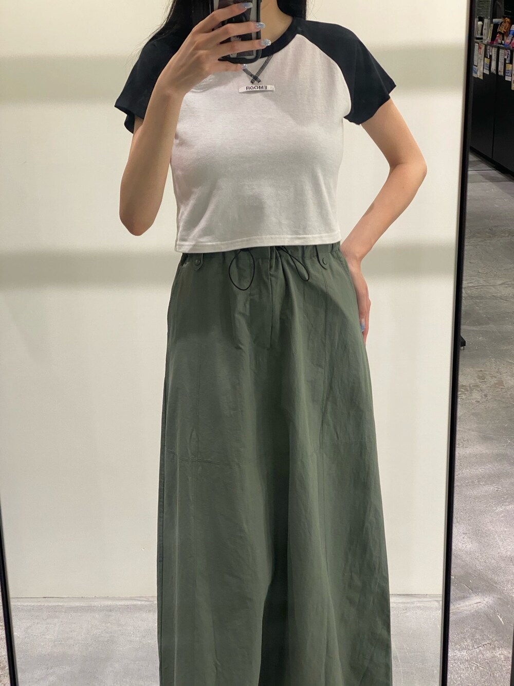 グリーン系のスカート、ブラック系のTシャツ/カットソー、ブラック系のサンダルを着用したレディースの夏コーディネートの3枚目の写真