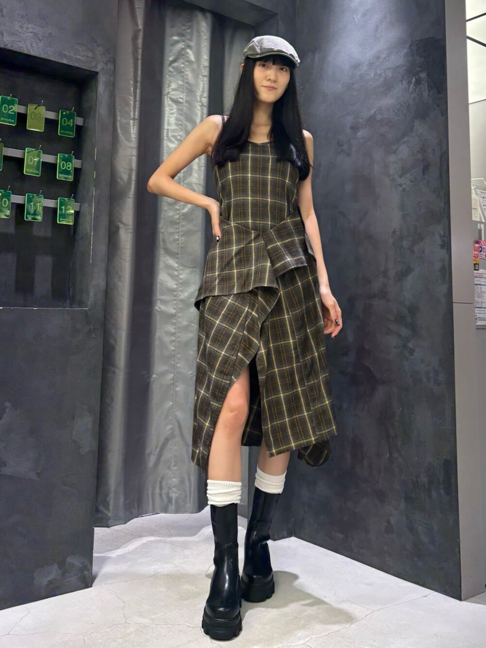 グリーン系のワンピース、ブラック系のブーツ、グレー系のハンチング/ベレー帽を着用したレディースの夏コーディネートの2枚目の写真