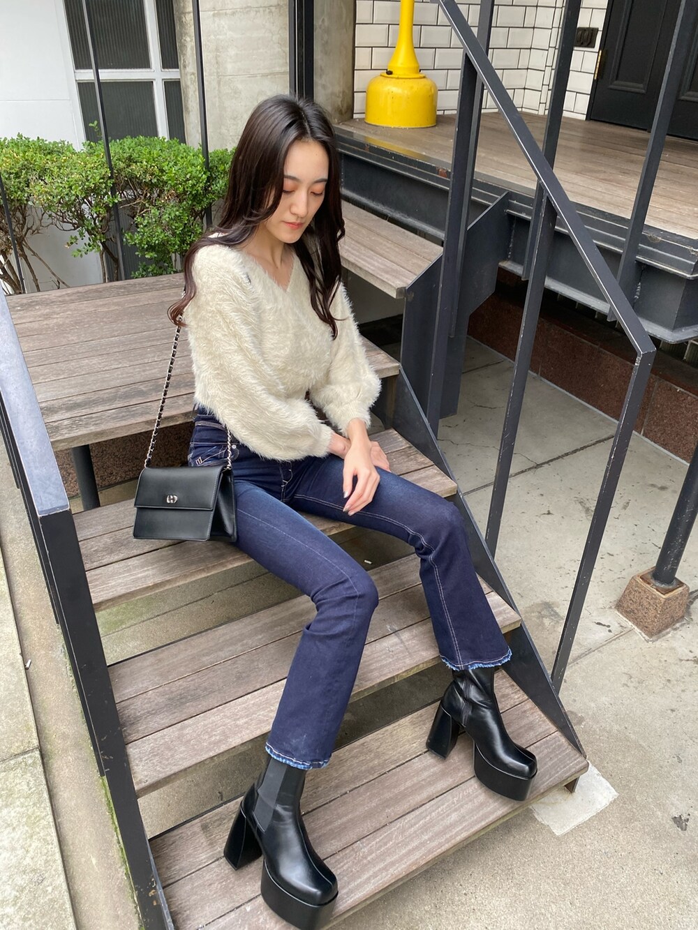 ブラック系のハンドバッグ、ブルー系のデニムパンツ、ホワイト系のニット/セーターを着用したレディースの冬コーディネートの4枚目の写真