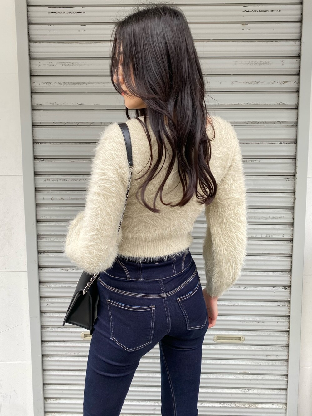 ブラック系のハンドバッグ、ブルー系のデニムパンツ、ホワイト系のニット/セーターを着用したレディースの冬コーディネートの6枚目の写真