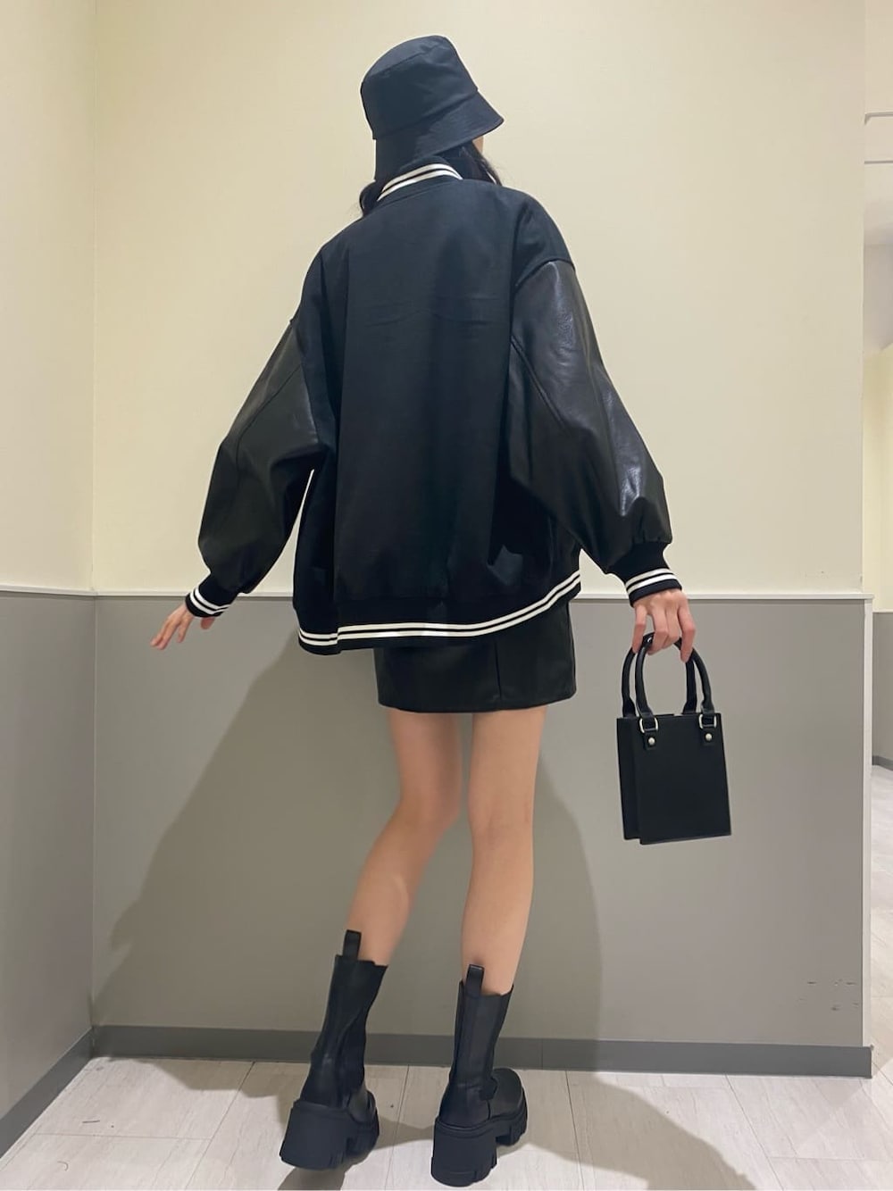 ブラック系のブーツ、ブラック系のハンドバッグ、ホワイト系のニット/セーターを着用したレディースの秋コーディネートの4枚目の写真