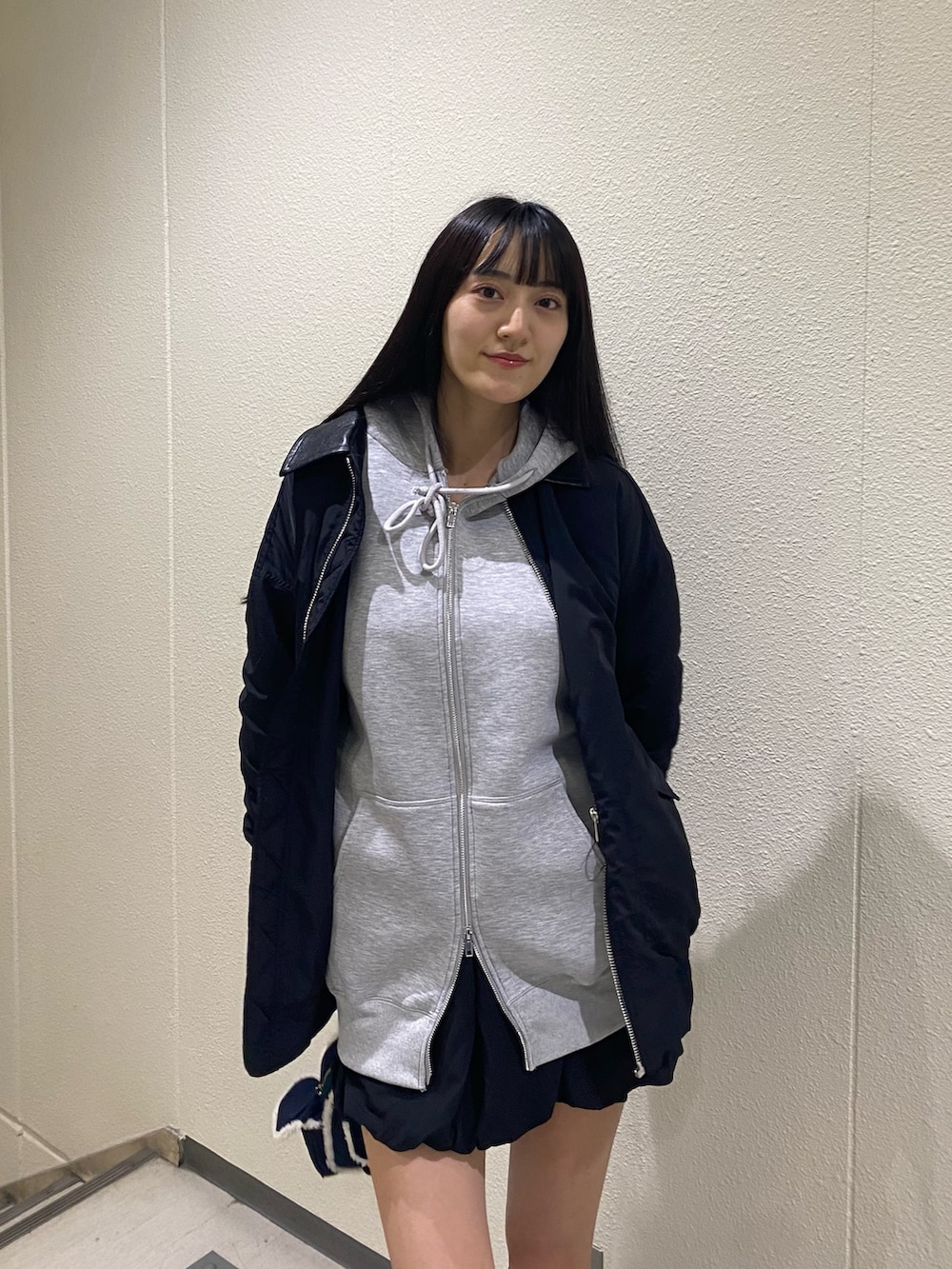 グレー系のパーカー、ブラック系のブルゾン、ブルー系のハンドバッグを着用したレディースの秋コーディネートの6枚目の写真