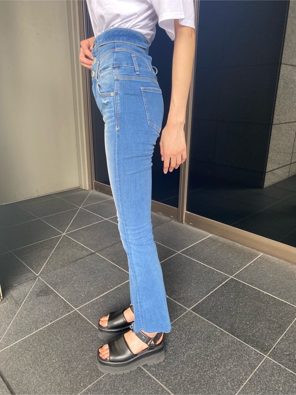 ブラック系のサンダル、ブルー系のデニムパンツ、ホワイト系のTシャツ/カットソーを着用したレディースの夏コーディネートの6枚目の写真