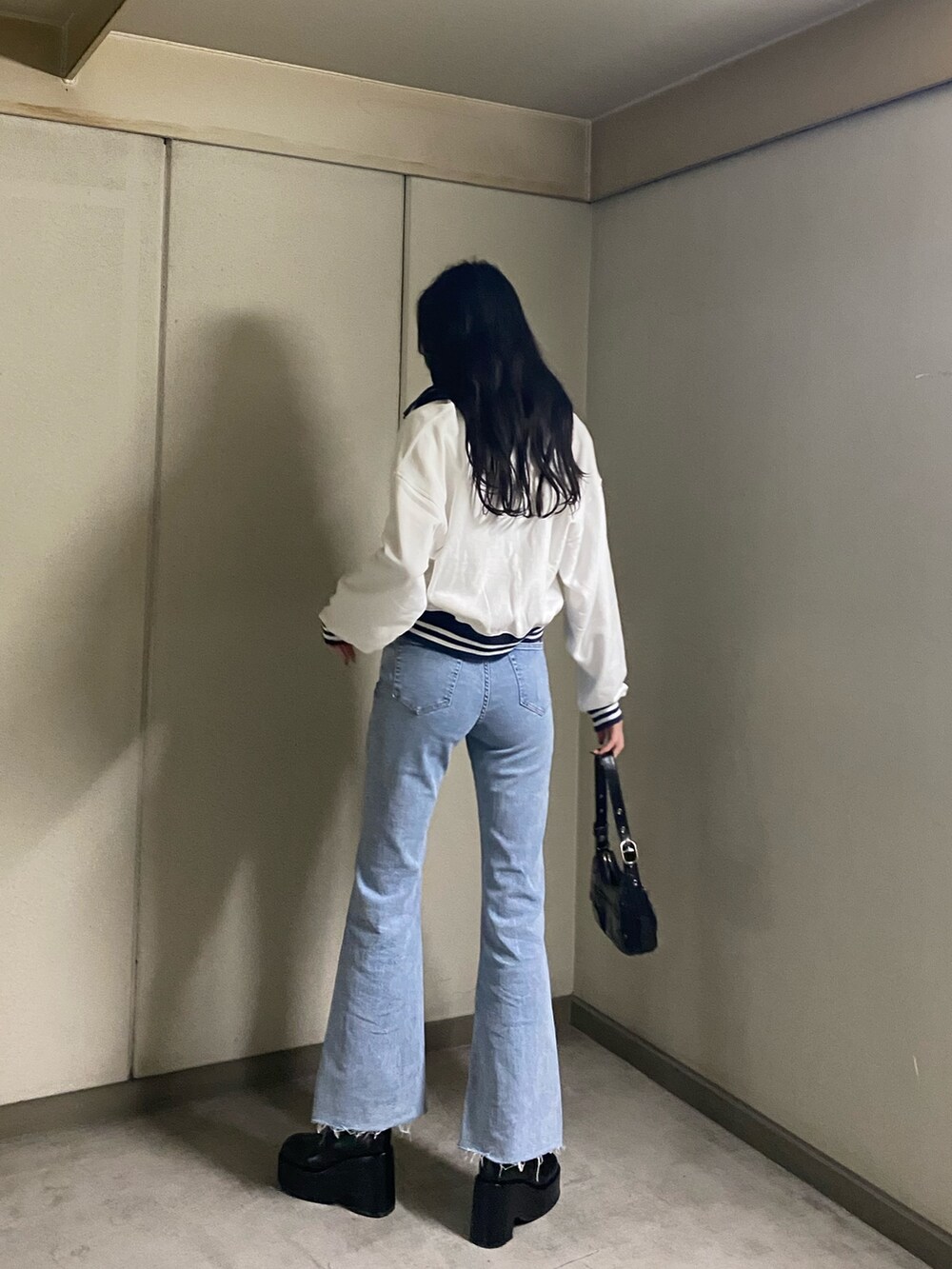 ホワイト系のTシャツ/カットソー、ブルー系のデニムパンツ、ブラック系のブーツを着用したレディースの春コーディネートの4枚目の写真