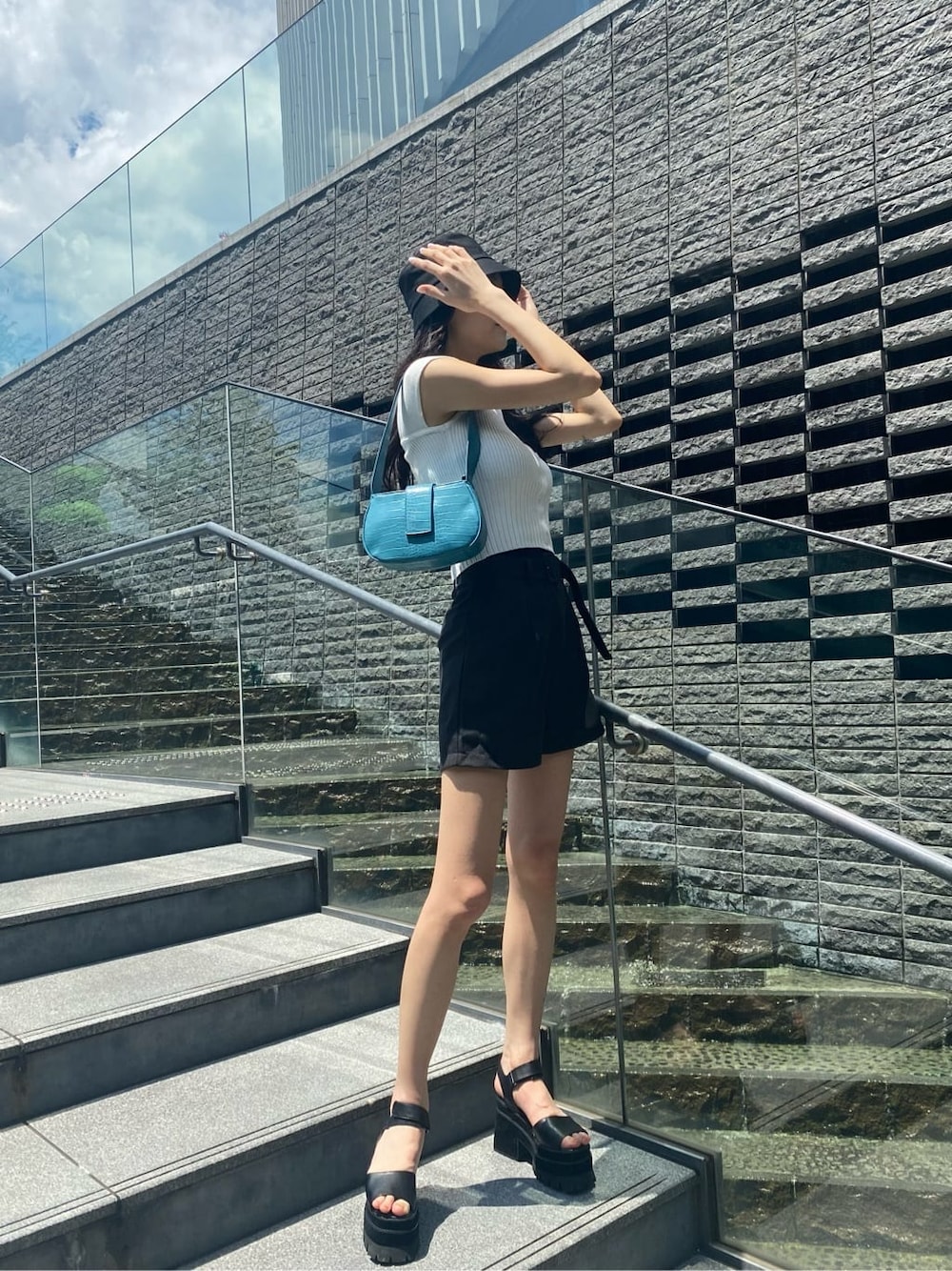 ブルー系のハンドバッグ、ブラック系のその他パンツ、ブラック系のサンダルを着用したレディースの夏コーディネートの2枚目の写真