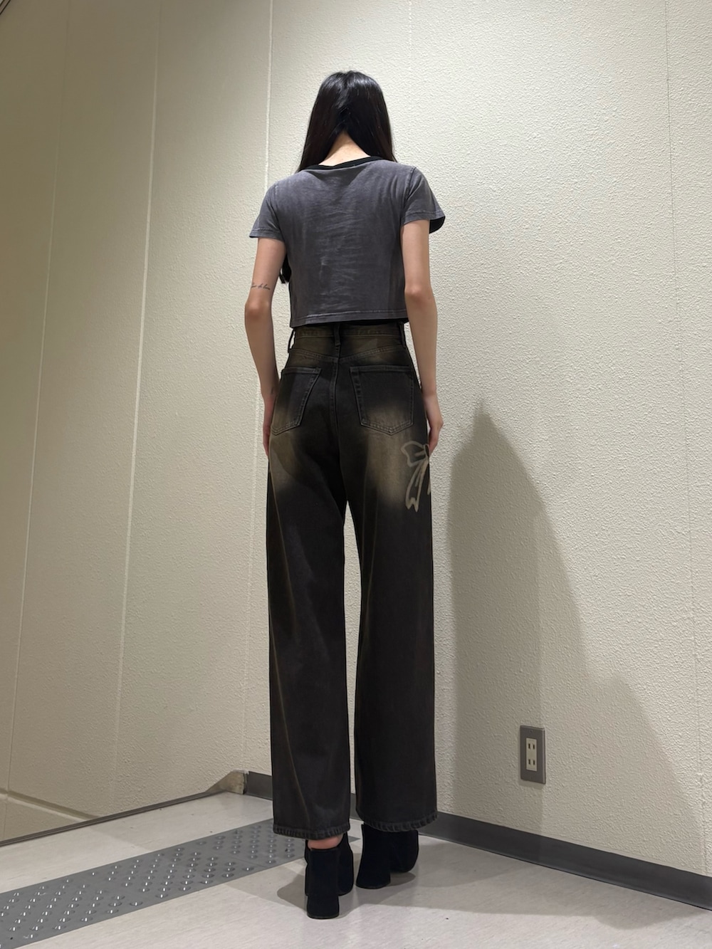 ブラック系のデニムパンツ、ブラック系のサンダル、グレー系のTシャツ/カットソーを着用したレディースの夏コーディネートの3枚目の写真