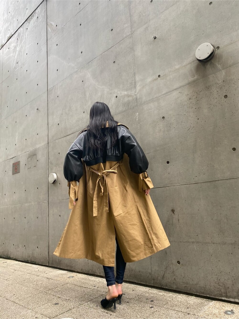 ブルー系のデニムパンツ、ベージュ系のトレンチコート、ブラック系のニット/セーターを着用したレディースの秋コーディネートの2枚目の写真