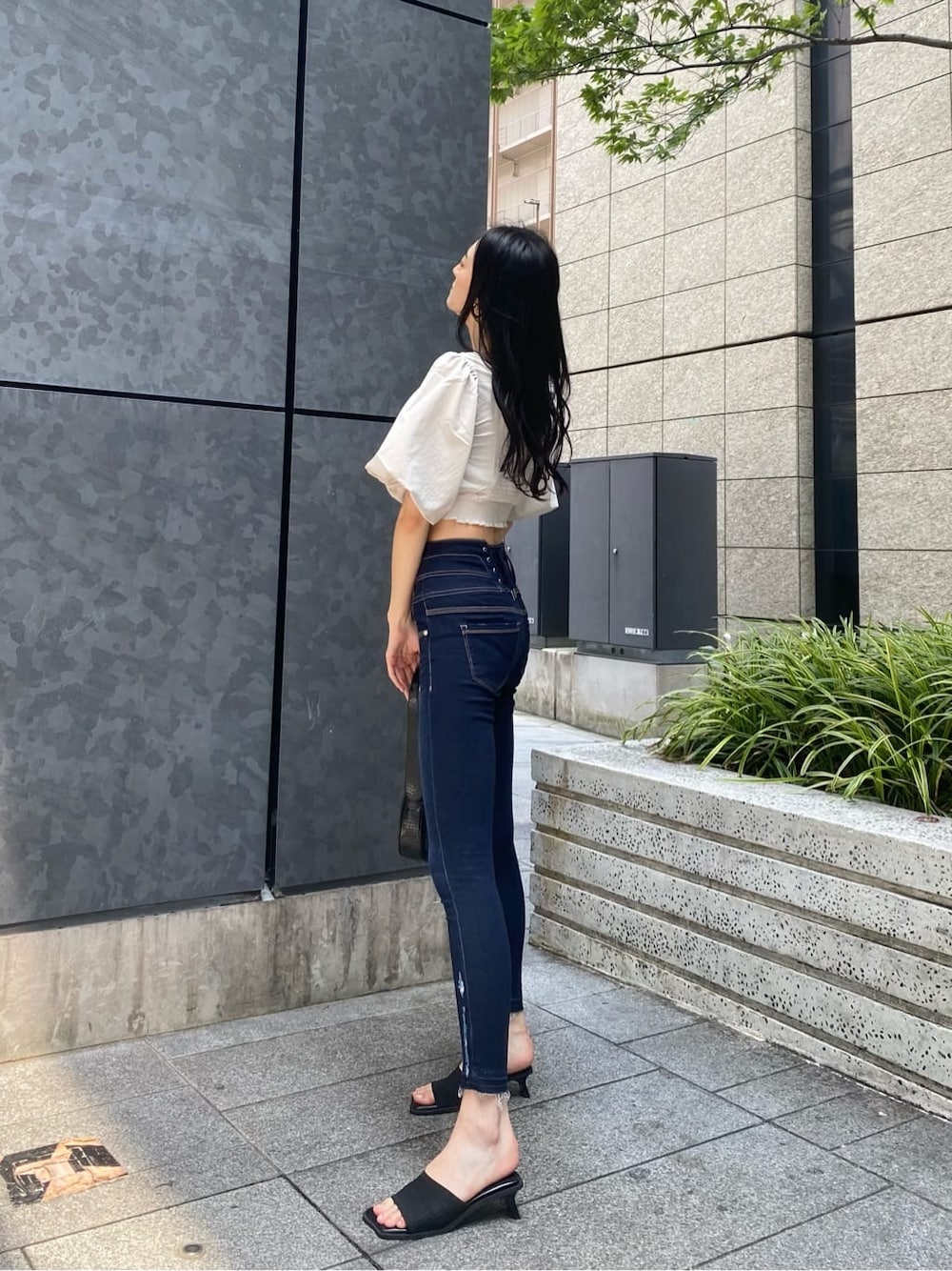 ブルー系のデニムパンツ、ホワイト系のTシャツ/カットソー、ブラック系のサンダルを着用したレディースの夏コーディネートの2枚目の写真