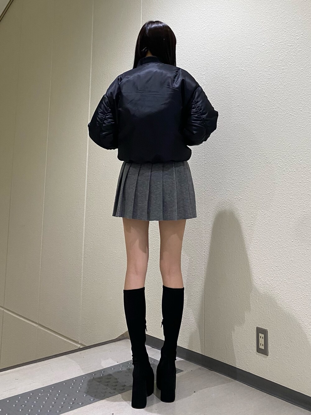 グレー系のスカート、ブラック系のブルゾン、その他のブーツを着用したレディースの秋コーディネートの3枚目の写真