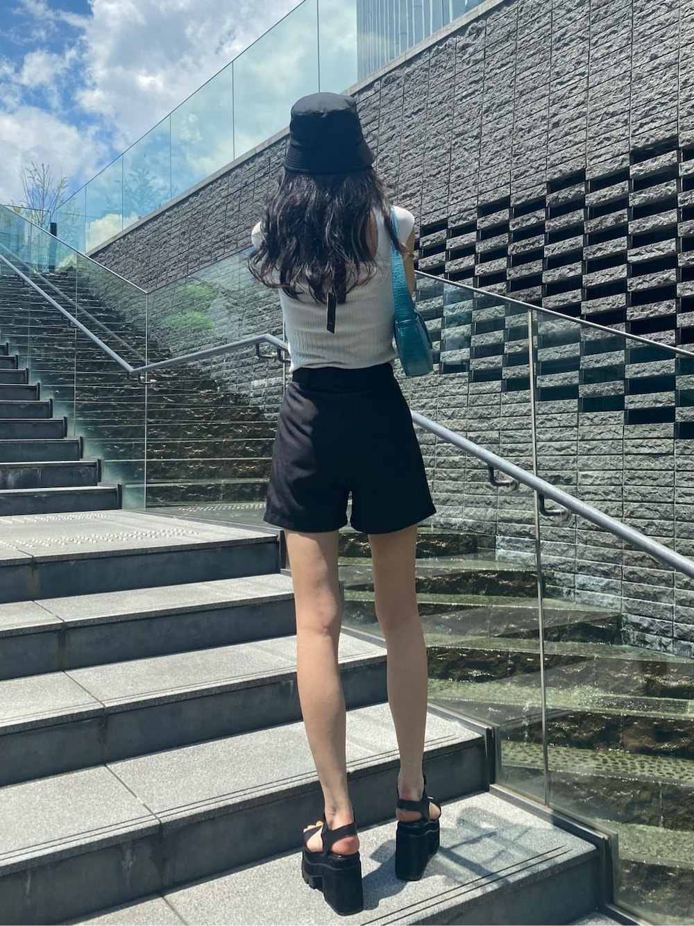 ブルー系のハンドバッグ、ブラック系のその他パンツ、ブラック系のサンダルを着用したレディースの夏コーディネートの3枚目の写真