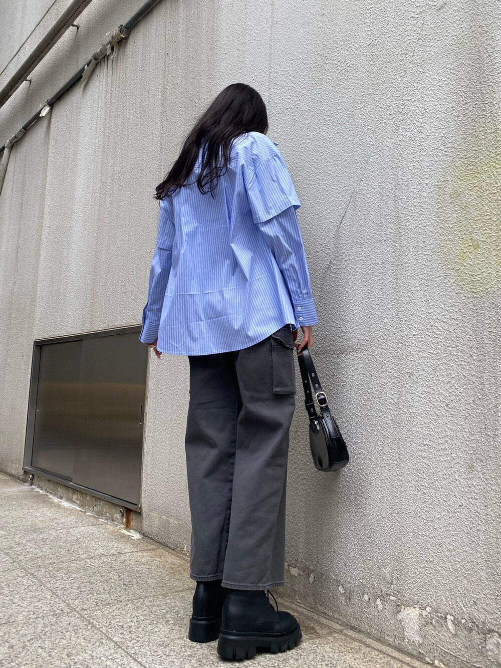 ブラック系のデニムパンツ、ブラック系のハンドバッグ、ブラック系のブーツを着用したレディースの春コーディネートの3枚目の写真