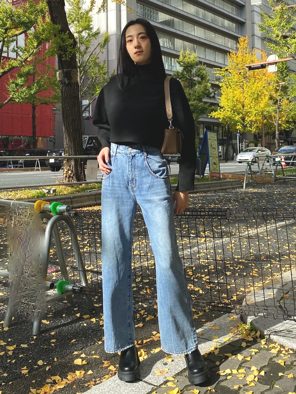 ブルー系のデニムパンツ、ブラック系のブーツ、ブラウン系のハンドバッグを着用したレディースの秋コーディネートの2枚目の写真