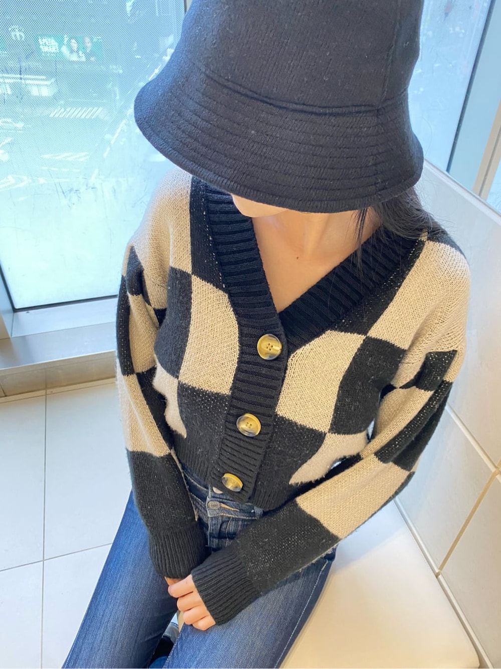 ブルー系のデニムパンツ、ブラック系のカーディガン/ボレロ、ベージュ系のハンドバッグを着用したレディースの冬コーディネートの7枚目の写真