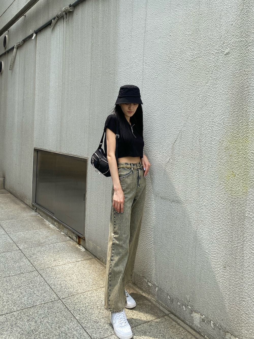 ブラック系のTシャツ/カットソー、ブラック系のハンドバッグ、ベージュ系のデニムパンツを着用したレディースの夏コーディネートの2枚目の写真