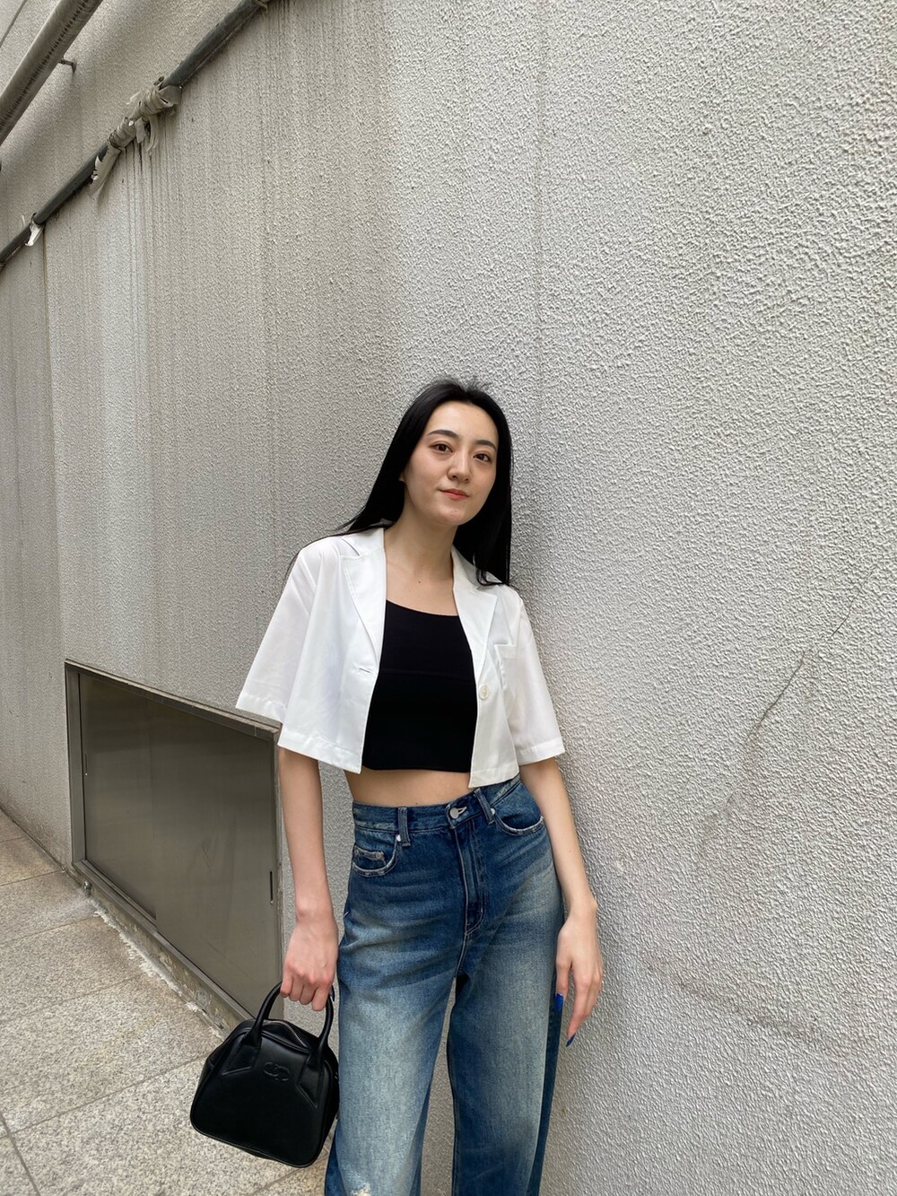 ブルー系のデニムパンツ、ブラック系のニット/セーター、ホワイト系のシャツ/ブラウスを着用したレディースの春コーディネートの6枚目の写真