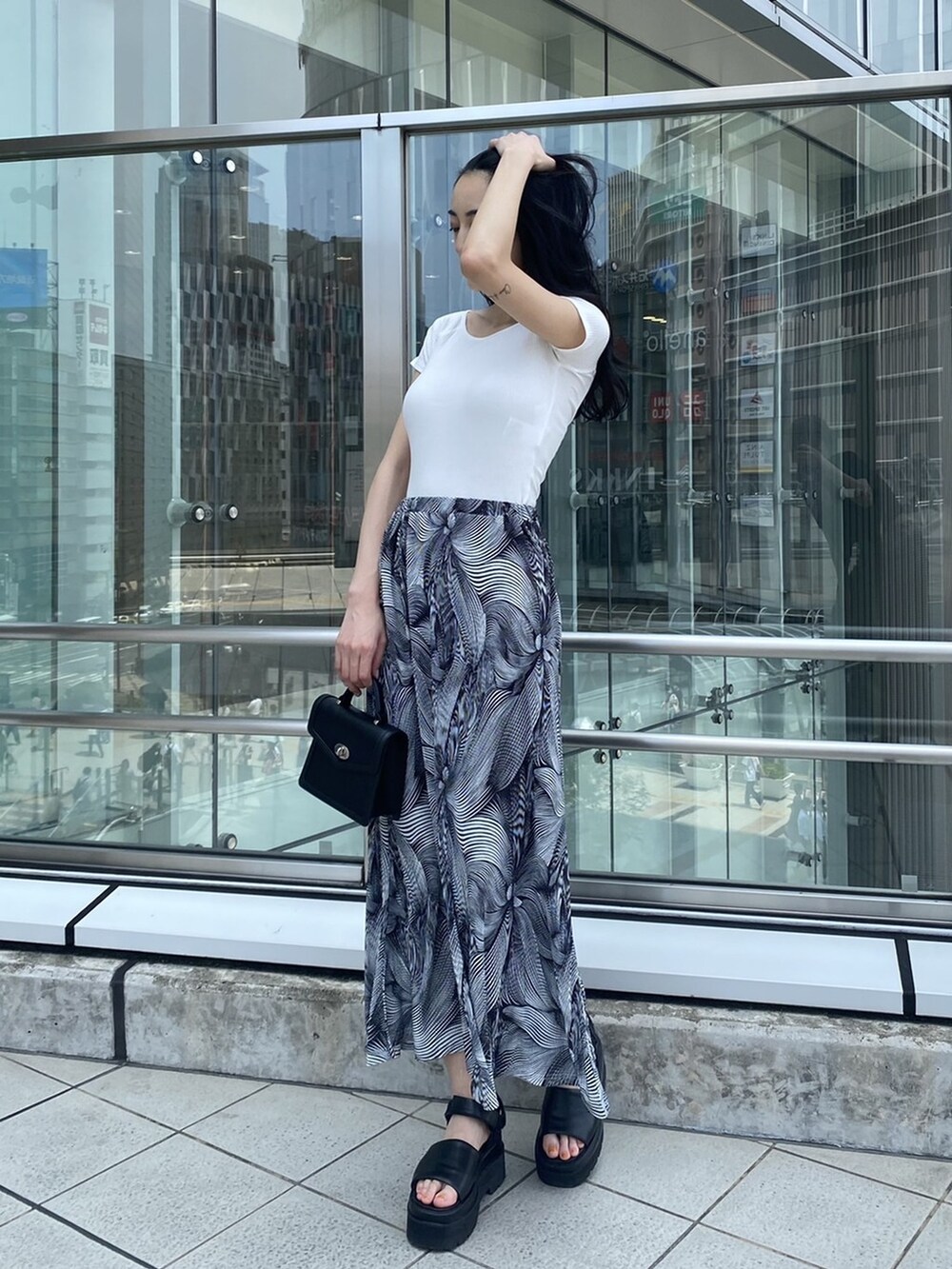 ブラック系のサンダル、ブラック系のハンドバッグ、その他のスカートを着用したレディースの夏コーディネートの2枚目の写真