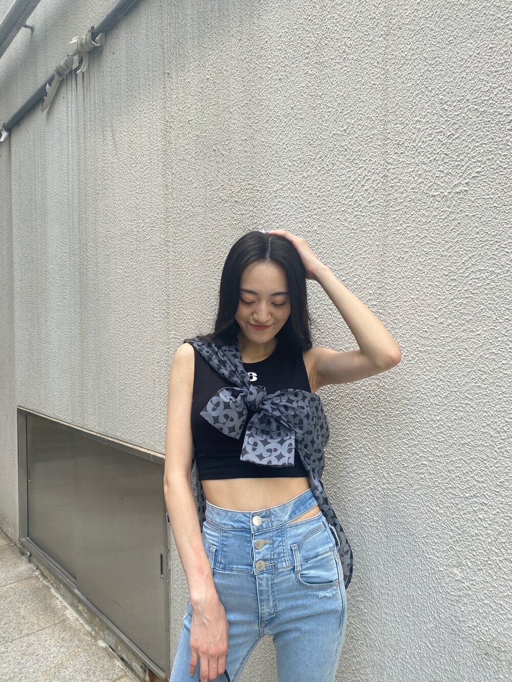 ブルー系のデニムパンツ、ブラック系のハンドバッグ、ブラック系のサンダルを着用したレディースの夏コーディネートの6枚目の写真