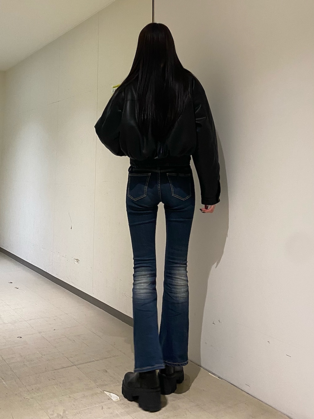 ブルー系のデニムパンツ、ホワイト系のニット/セーター、ブラック系のブルゾンを着用したレディースの秋コーディネートの3枚目の写真