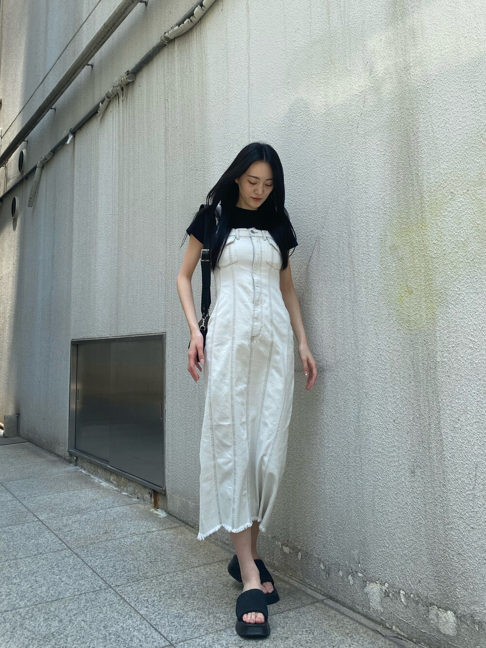 ブラック系のTシャツ/カットソー、ホワイト系のワンピース、ブラック系のショルダーバッグを着用したレディースの夏コーディネートの3枚目の写真