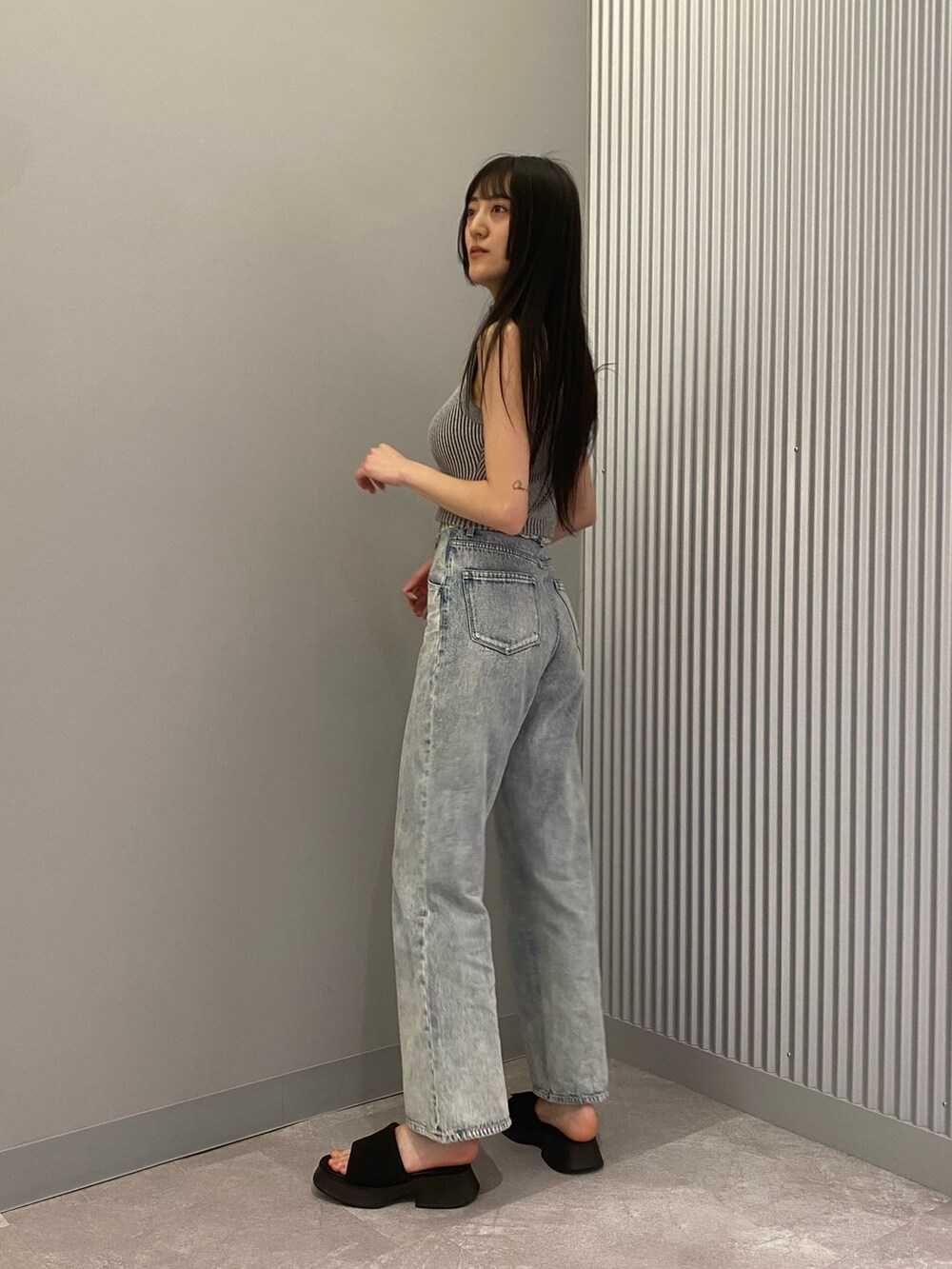 ブルー系のデニムパンツ、グレー系のニット/セーター、ブラック系のサンダルを着用したレディースの春コーディネートの2枚目の写真