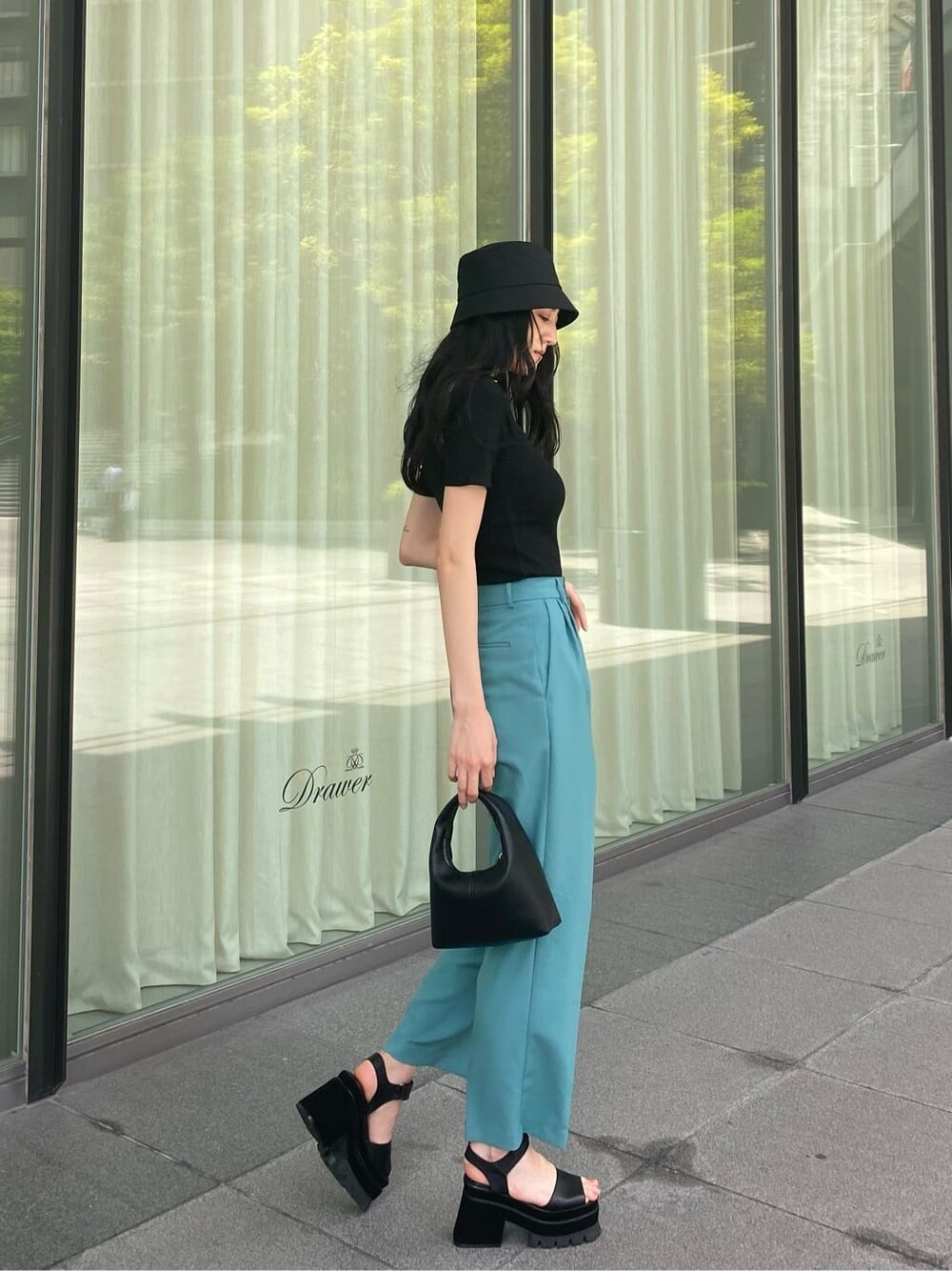 ブルー系のその他パンツ、ブラック系のサンダル、ブラック系のハンドバッグを着用したレディースの夏コーディネートの3枚目の写真