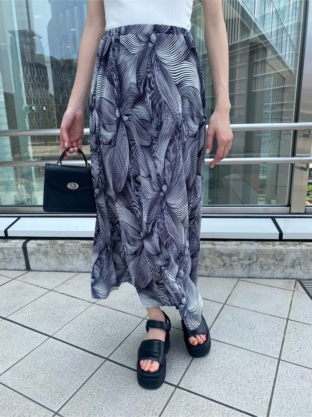 ブラック系のサンダル、ブラック系のハンドバッグ、その他のスカートを着用したレディースの夏コーディネートの5枚目の写真