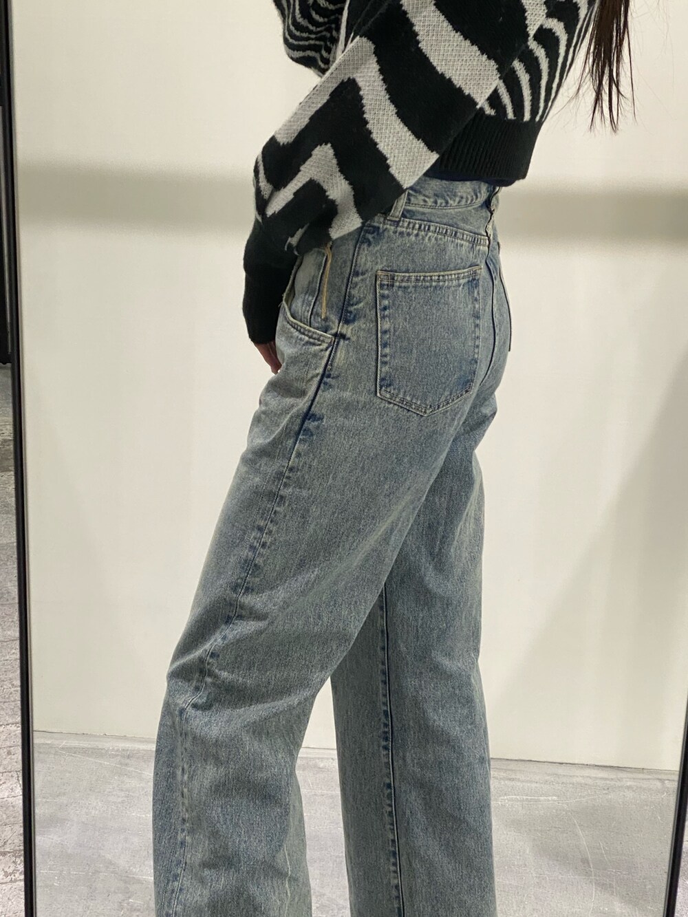 ブルー系のデニムパンツ、ブラック系のニット/セーター、ブラック系のブーツを着用したレディースの冬コーディネートの8枚目の写真