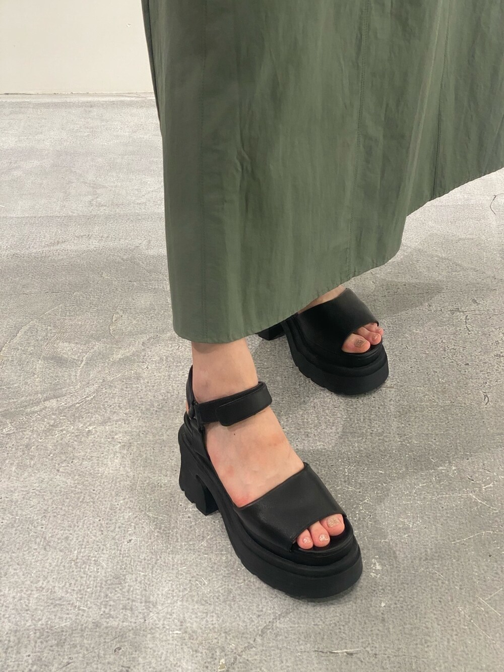 グリーン系のスカート、ブラック系のTシャツ/カットソー、ブラック系のサンダルを着用したレディースの夏コーディネートの8枚目の写真