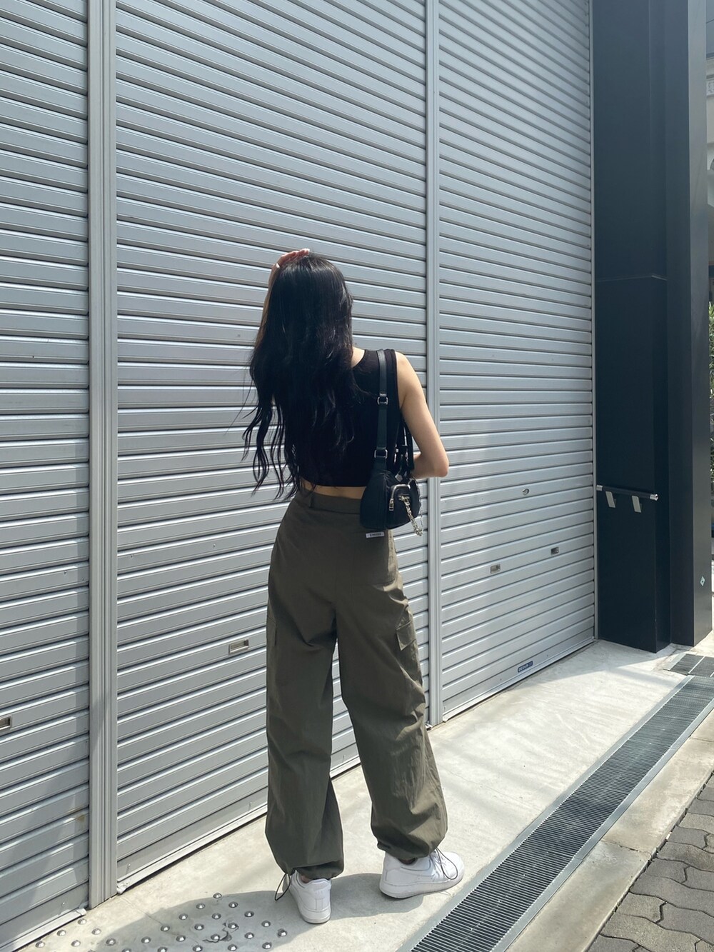 ベージュ系のカーゴパンツ、ブラック系のタンクトップ、ブラック系のハンドバッグを着用したレディースの夏コーディネートの3枚目の写真
