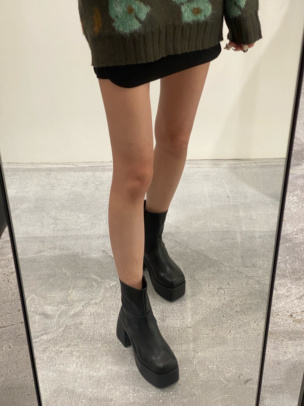 グリーン系のニット/セーター、ブラック系のスカート、ブラック系のブーツを着用したレディースの秋コーディネートの5枚目の写真