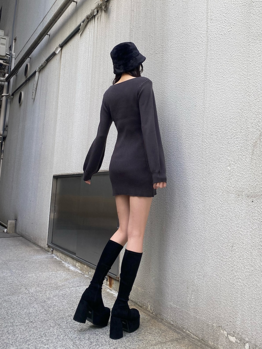 グレー系のワンピース、ブラック系のブーツ、ブラック系のハットを着用したレディースの冬コーディネートの3枚目の写真