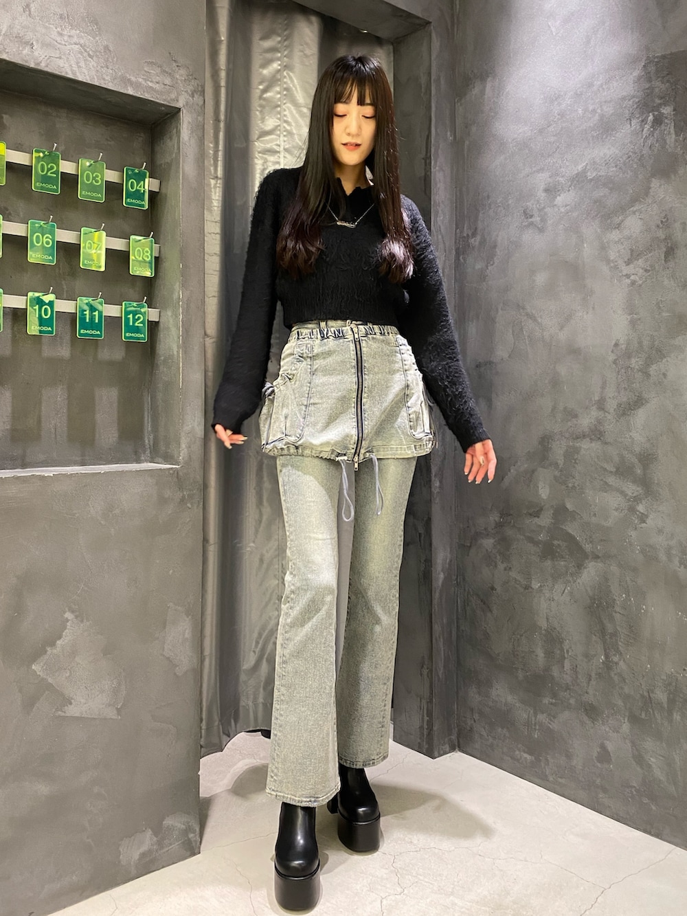 ブルー系のデニムパンツ、ブラック系のニット/セーター、ブラック系のブーツを着用したレディースの秋コーディネートの2枚目の写真