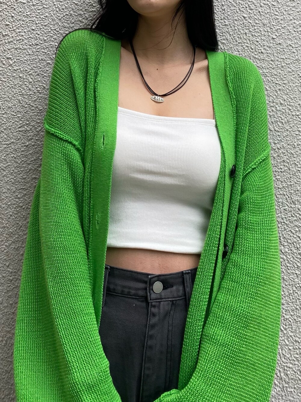 グリーン系のカーディガン/ボレロ、ホワイト系のキャミソール、ブラック系のデニムパンツを着用したレディースの春コーディネートの7枚目の写真