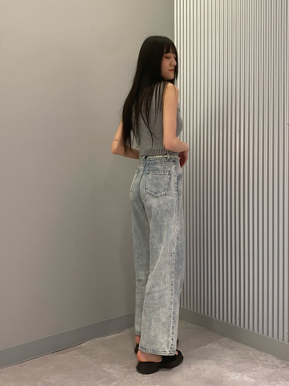 ブルー系のデニムパンツ、グレー系のニット/セーター、ブラック系のサンダルを着用したレディースの春コーディネートの4枚目の写真